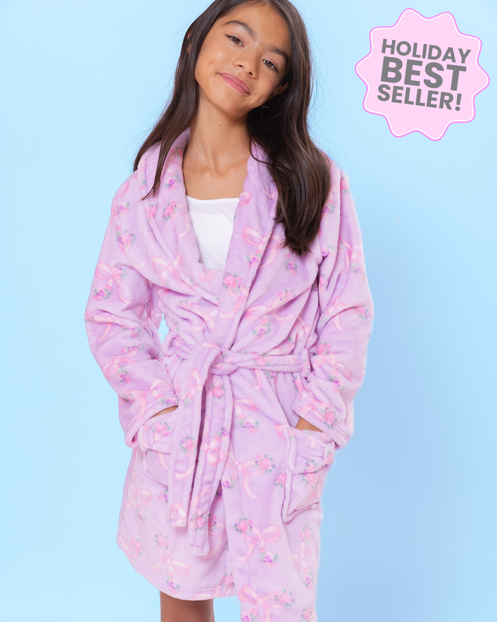 Young girl wearing a lavender floral bow print robe with a blue background