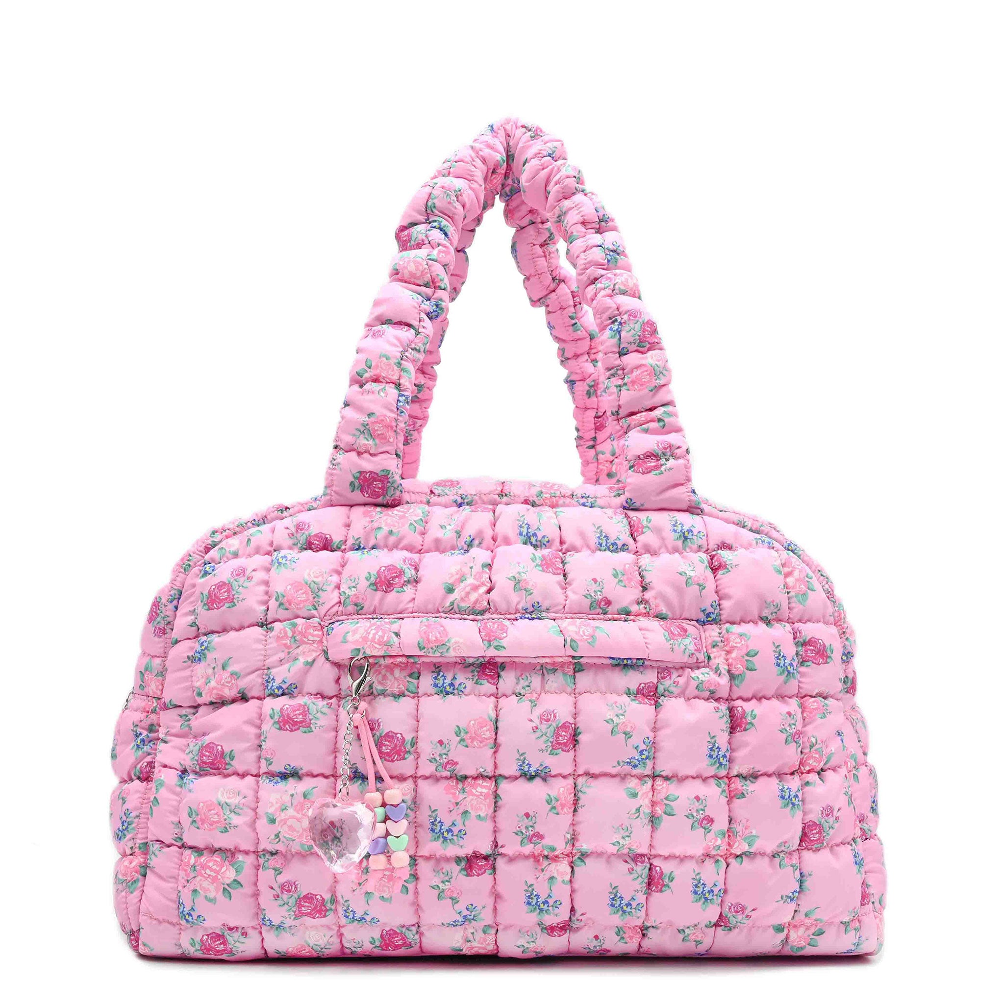 front facing view of a pink medium sized quilted scrunch nylon duffle bag with a floral print and front beaded zipper pocket with a crystal heart charm