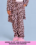 A child wearing a pink leopard-print pajama pants, standing against a light blue background. A pink text banner at the bottom reads 'MODEL IS 4'5" AND 10 YEARS OLD WEARING SIZE MEDIUM'.
