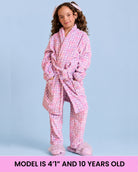 A model wearing a purple and white gingham bath robe in front of a light blue background with text that reads "model is 4''1" and 10 years old"