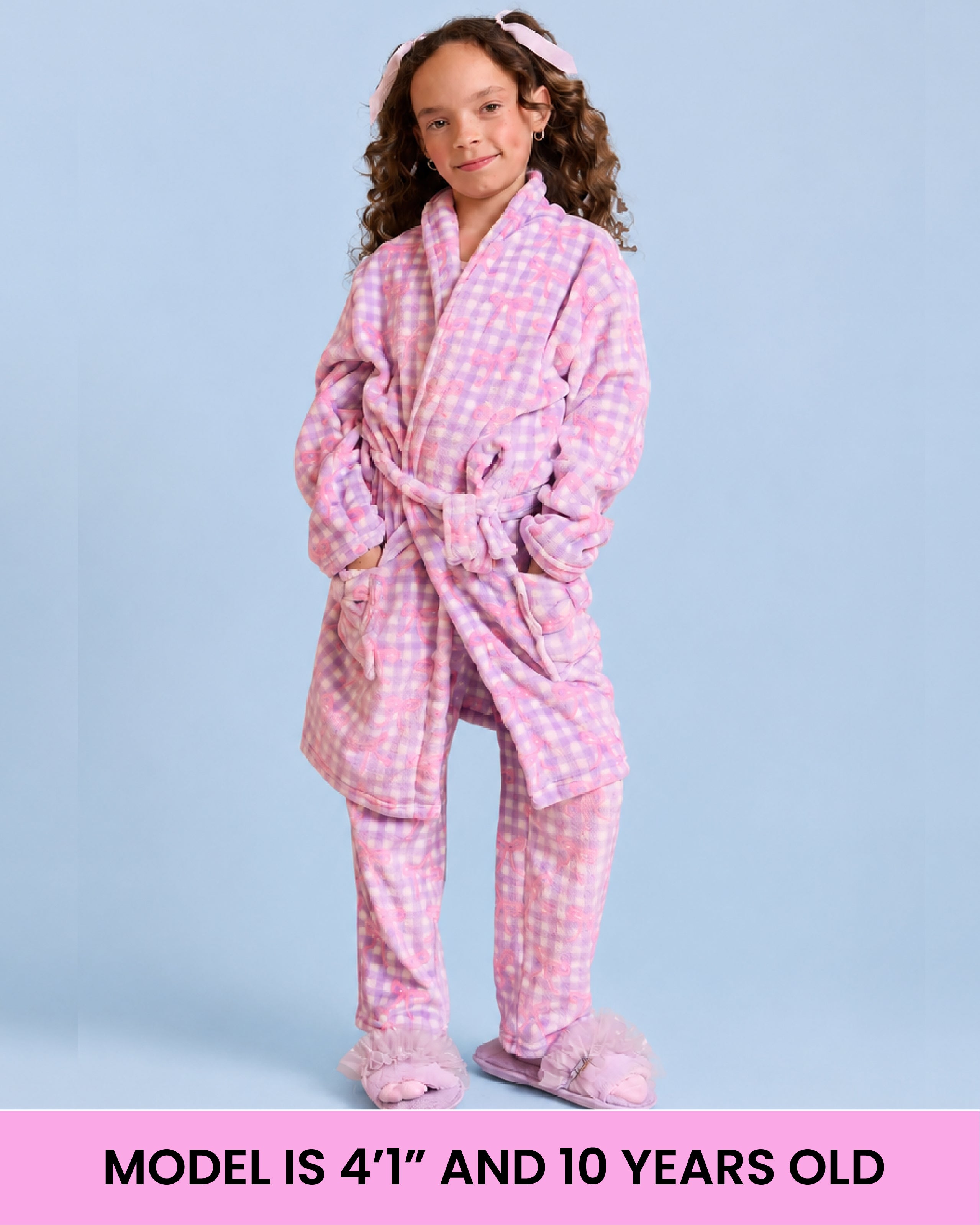 A model wearing a purple and white gingham bath robe in front of a light blue background with text that reads "model is 4''1" and 10 years old"