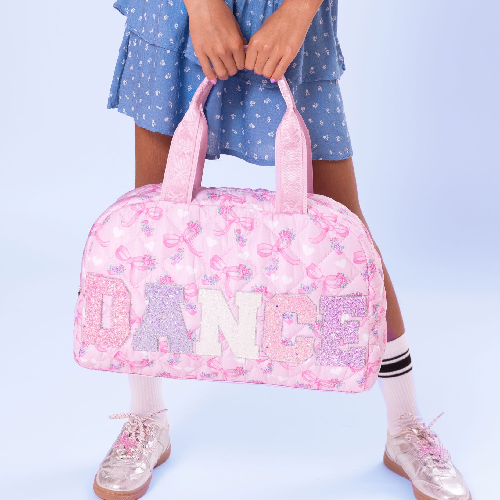 front view of a pink quilted medium "dance" duffle with a floral & bow print