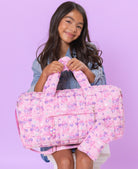 view of model holding large quilted pink scrunch bag with a cherry & heart print 