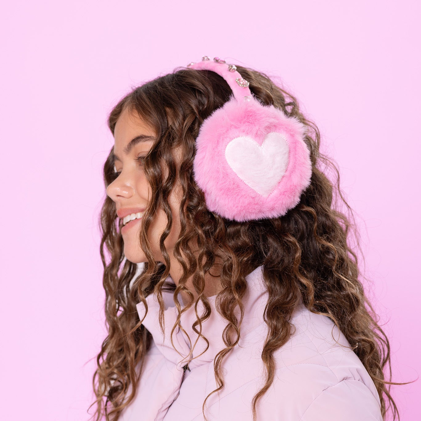 model wearing pink fluffy earmuffs with heart design & gems on the crown
