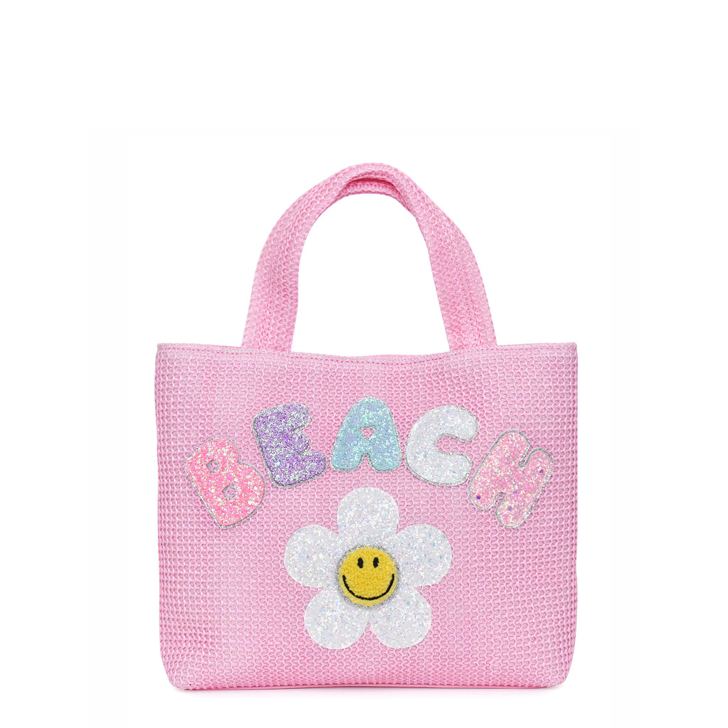 Front view of mini pink straw 'Beach' tote bag with smiley daisy patch