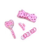 image of a cherry-printed spa kit  with a hairbrush, spa headband, hair ties, & claw clip 