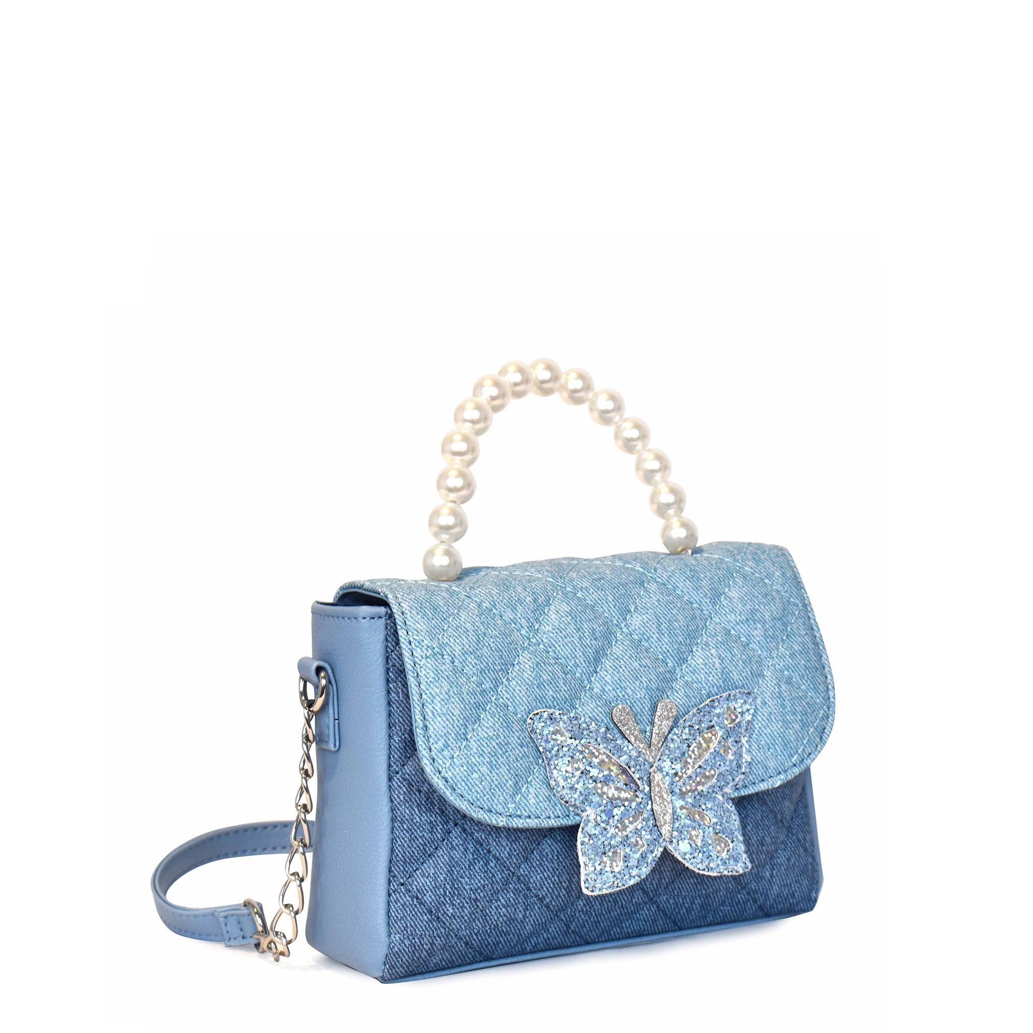 Side view of a two-toned denim quilted flap top crossbody with a pearl top handle and glitter butterfly closure button patch