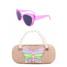 front view of a straw sunglass case with pearl top handles and a glitter butterfly patch along with a pair of glitter sunglasses 