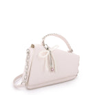 side view of a t view of white angled flap front crossbody bag with a pearl bow charm