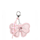 A pink bow-shaped keychain charm with silver-tone metal hardware, decorative pink and white faux pearls, and a central faceted pink rhinestone on a plain white background.