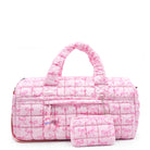 front facing view of a pink large sized quilted scrunch nylon duffle bag with a bow print and front beaded zipper pocket with a crystal heart charm and matching detachable coin pouch