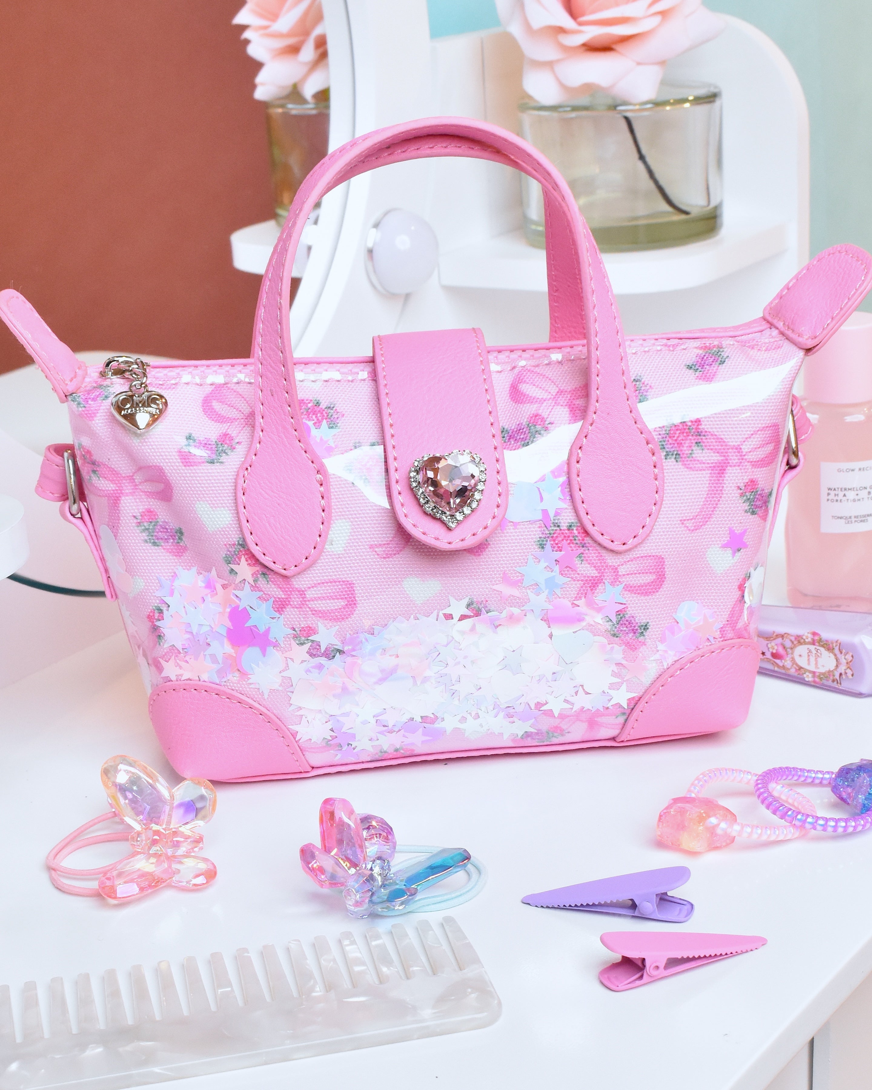 Pink pouchette style handbag with bow & floral print with confetti  on top of vanity 