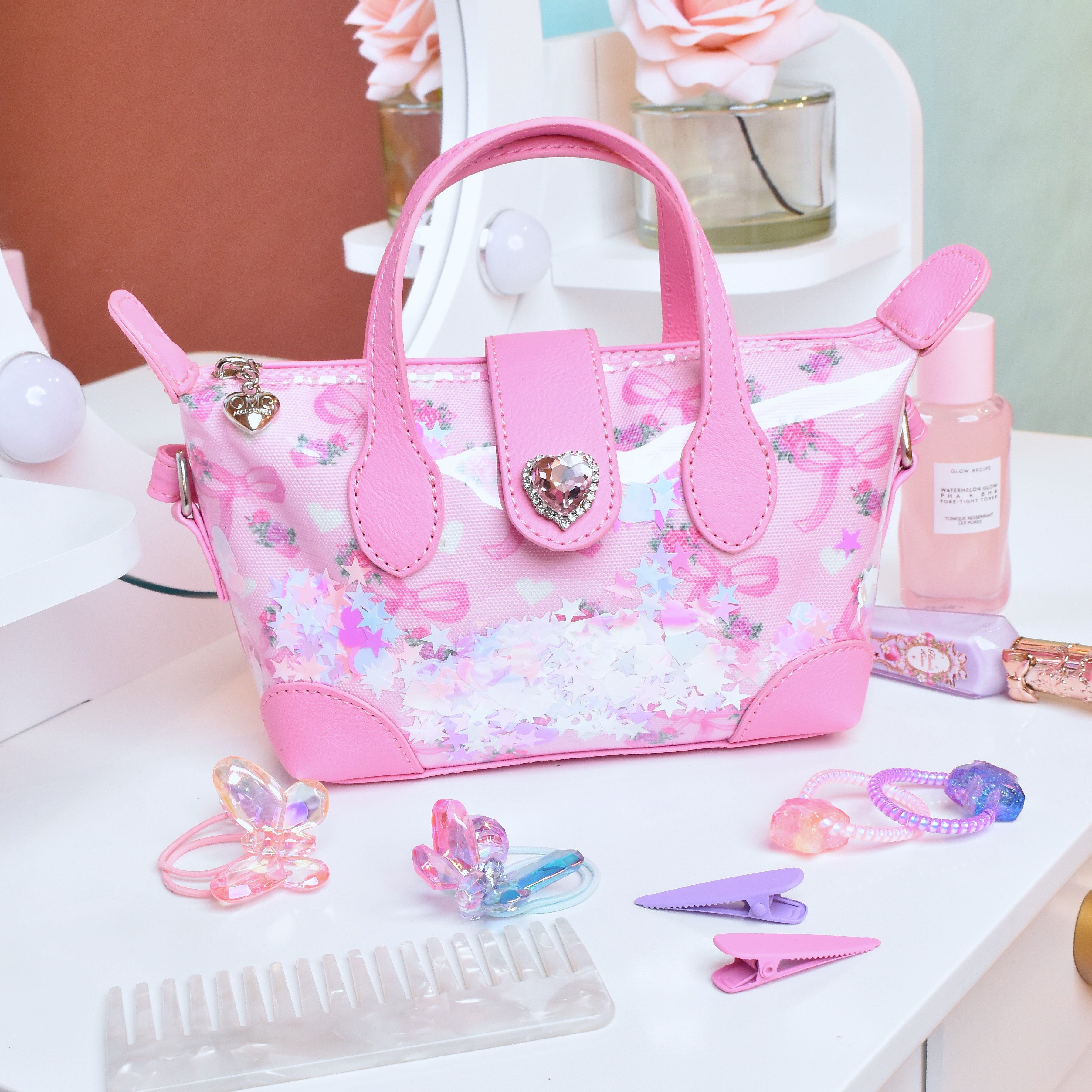 Pink pouchette style handbag with bow & floral print with confetti  on top of vanity 