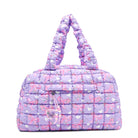 front facing view of a purple quilted scrunch medium sized duffe bag with a bow/floral/heart print and front zipper pocket with a beaded zipper and crystal heart charm