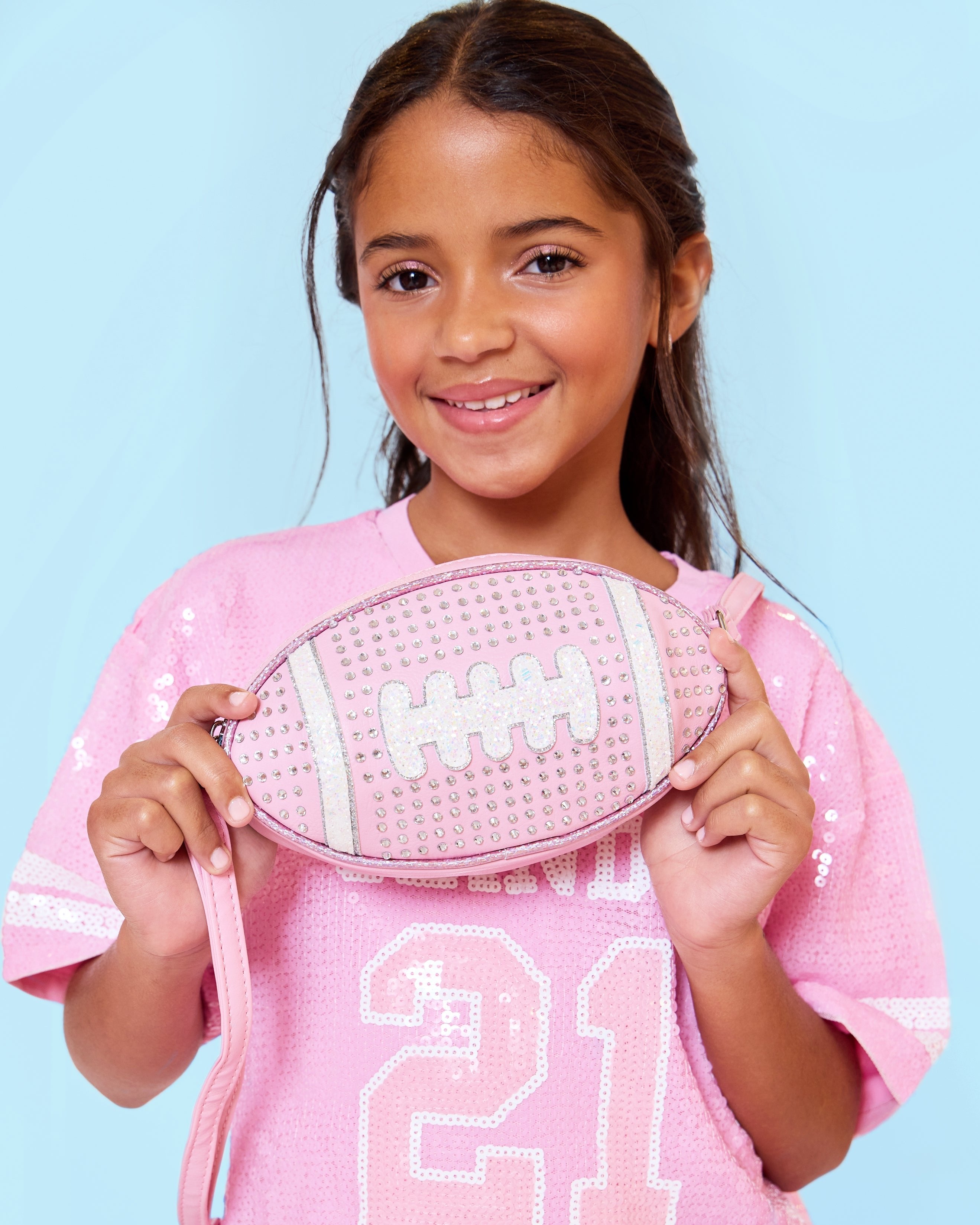  photoshoot photo of a rhinestone covered pink football shaped crossbody bag