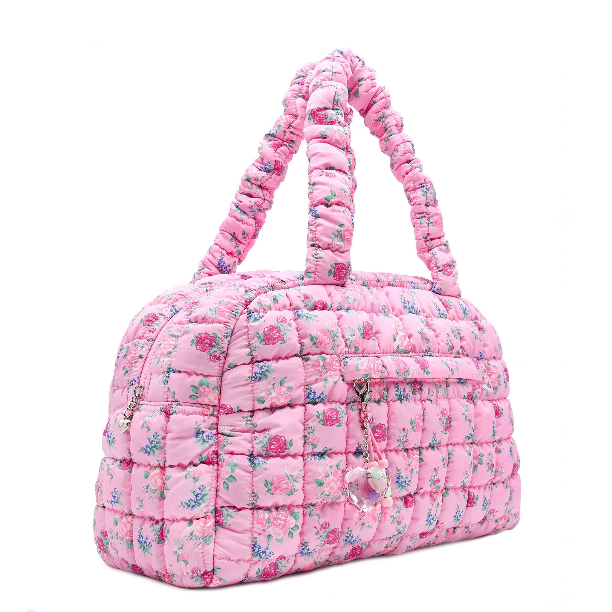 3/4 facing view of a pink medium sized quilted scrunch nylon duffle bag with a floral print and front beaded zipper pocket with a crystal heart charm