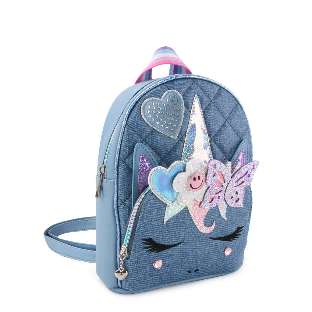 Side view of a denim quilted unicorn face mini backpack with glitter butterfly, heart, and happy face flower appliqués