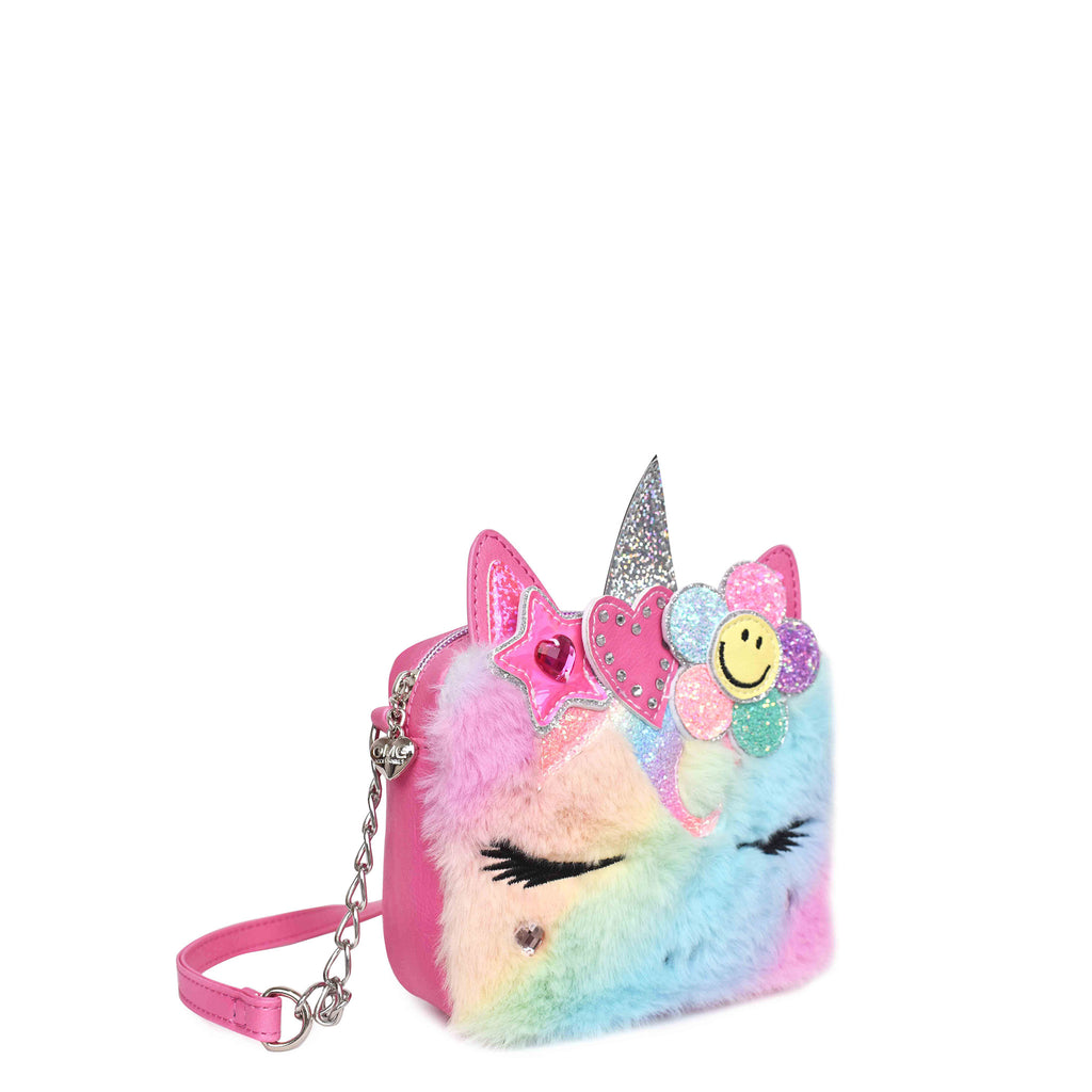 Side view of a rainbow plush unicorn face crossbody embellished with a glitter smiley face, rhinestone heart, and metallic star appliqués
