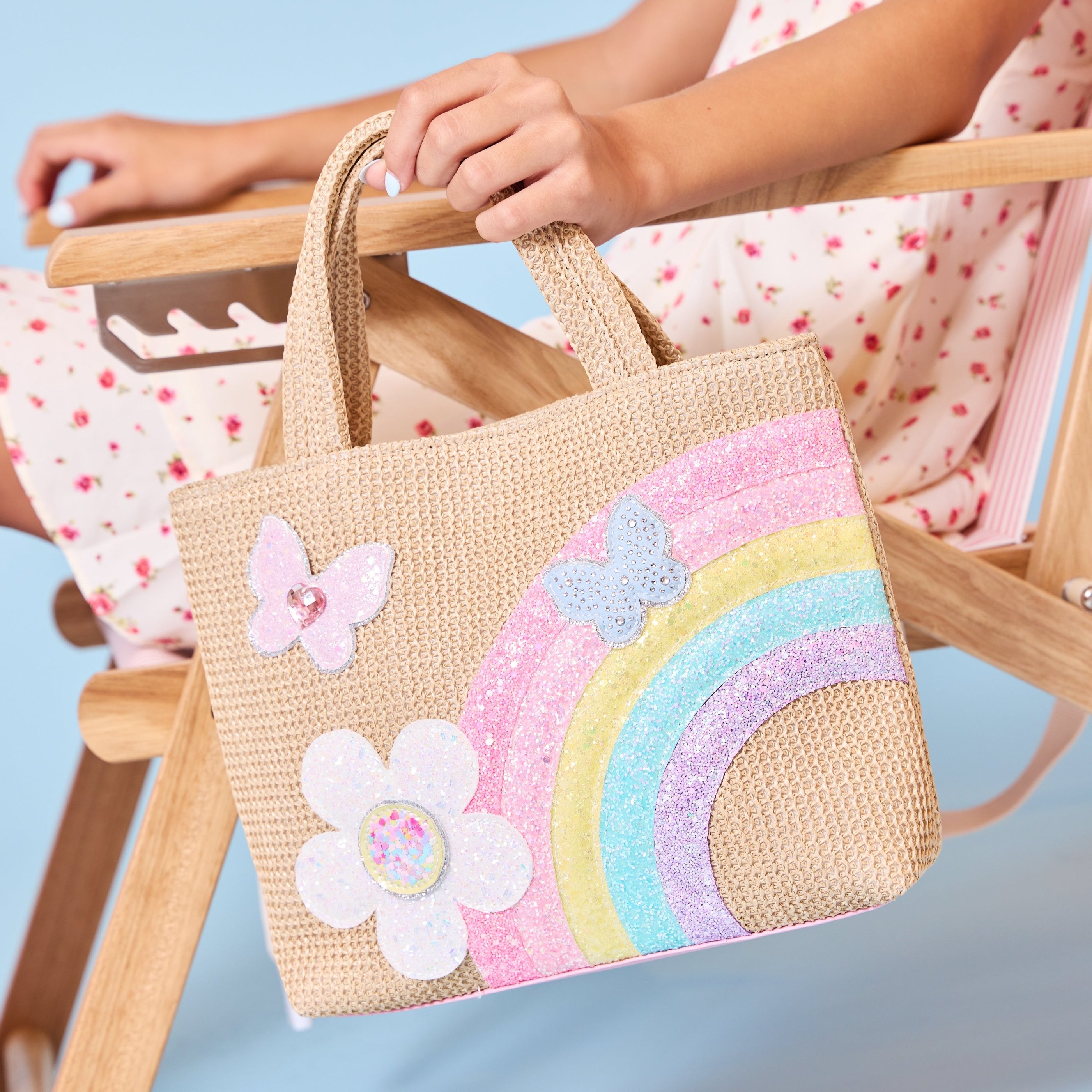 photoshoot photo of a straw mini tote bag with glitter rainbow & daisy appliqués 