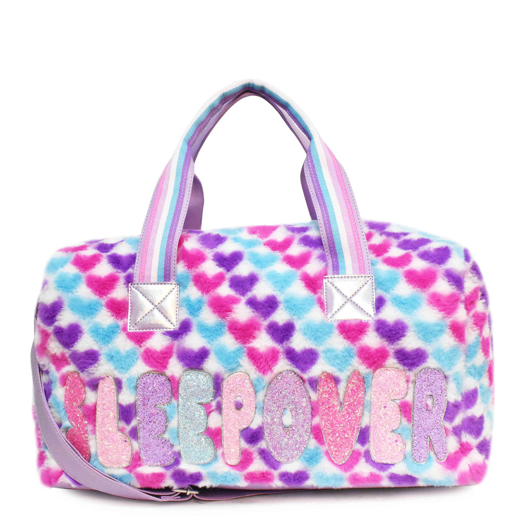 Front view of large plush multicolor heart-printed 'sleepover' duffle with glitter bubble-letter patches