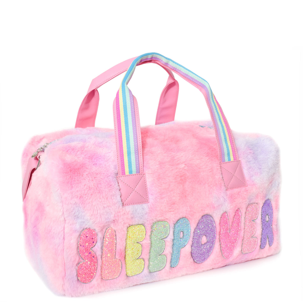 Side view of large pink tie dye plush 'sleepover' duffle with glitter bubble-letter patches
