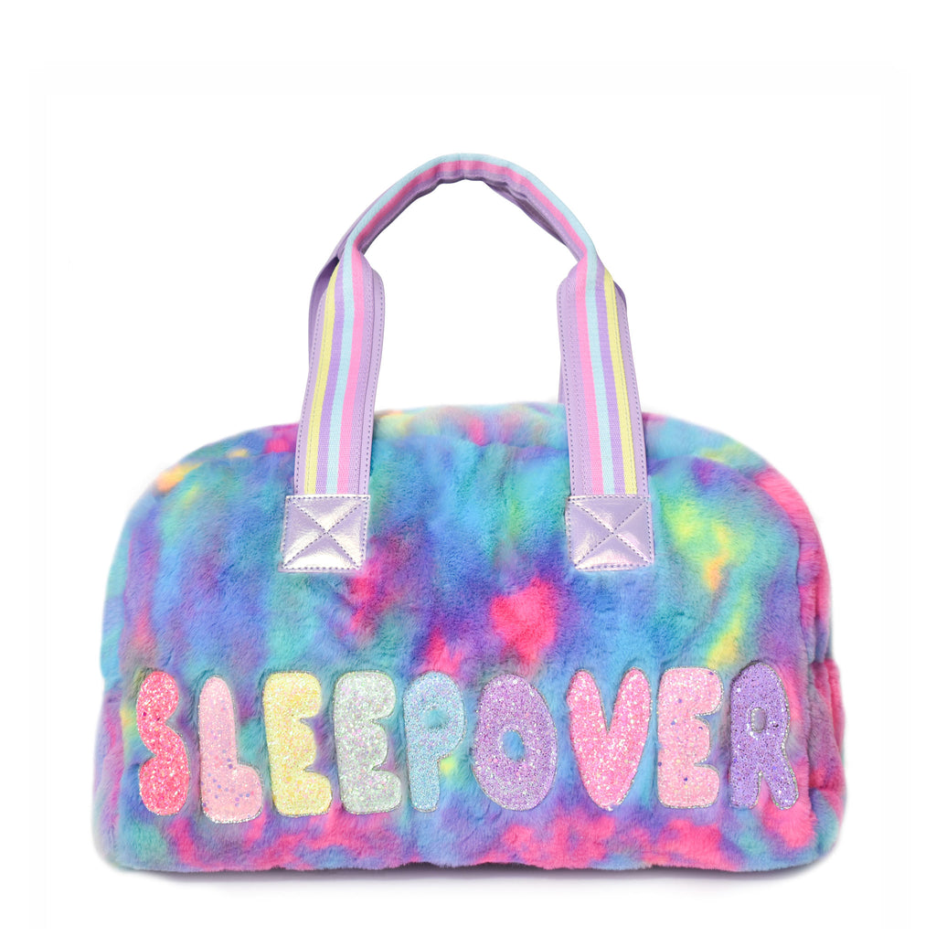 Front view of a medium plush tie dye 'sleepover' duffle with glitter bubble-letter patches