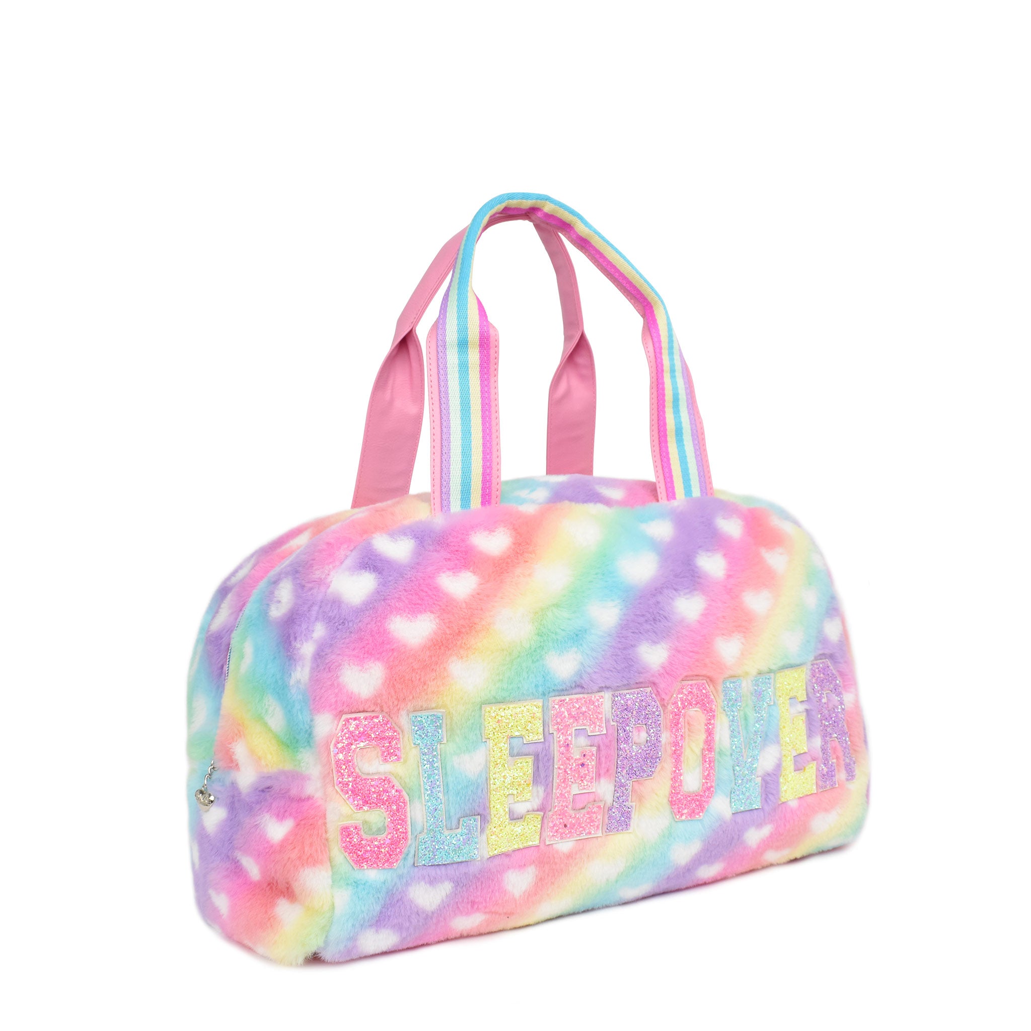 Side view of a rainbow ombre , heart-printed plush duffle bag with 'sleepover' glitter varsity letters
