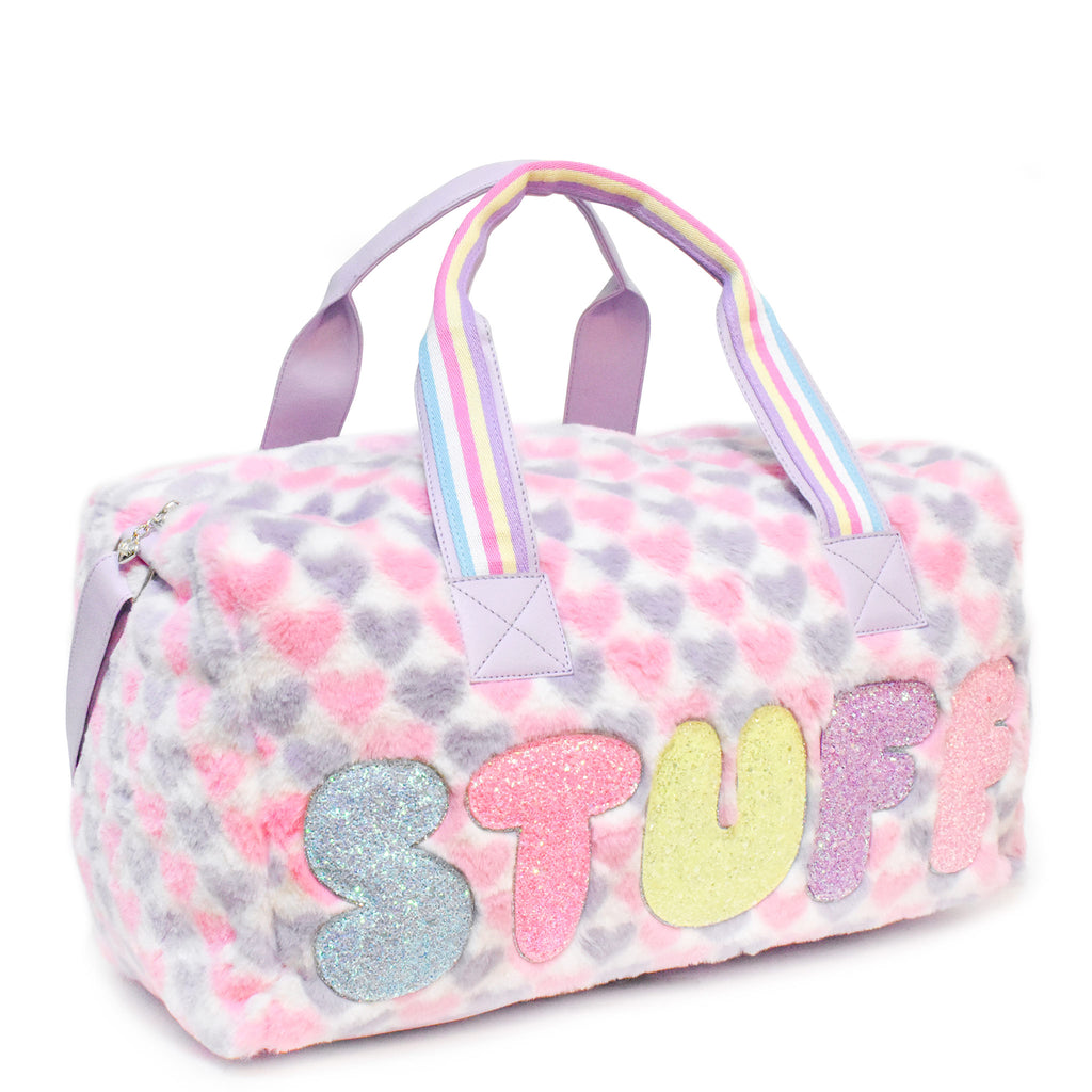 Side view of large plush pink and purple heart-printed 'stuff' duffle with glitter bubble-letter patches