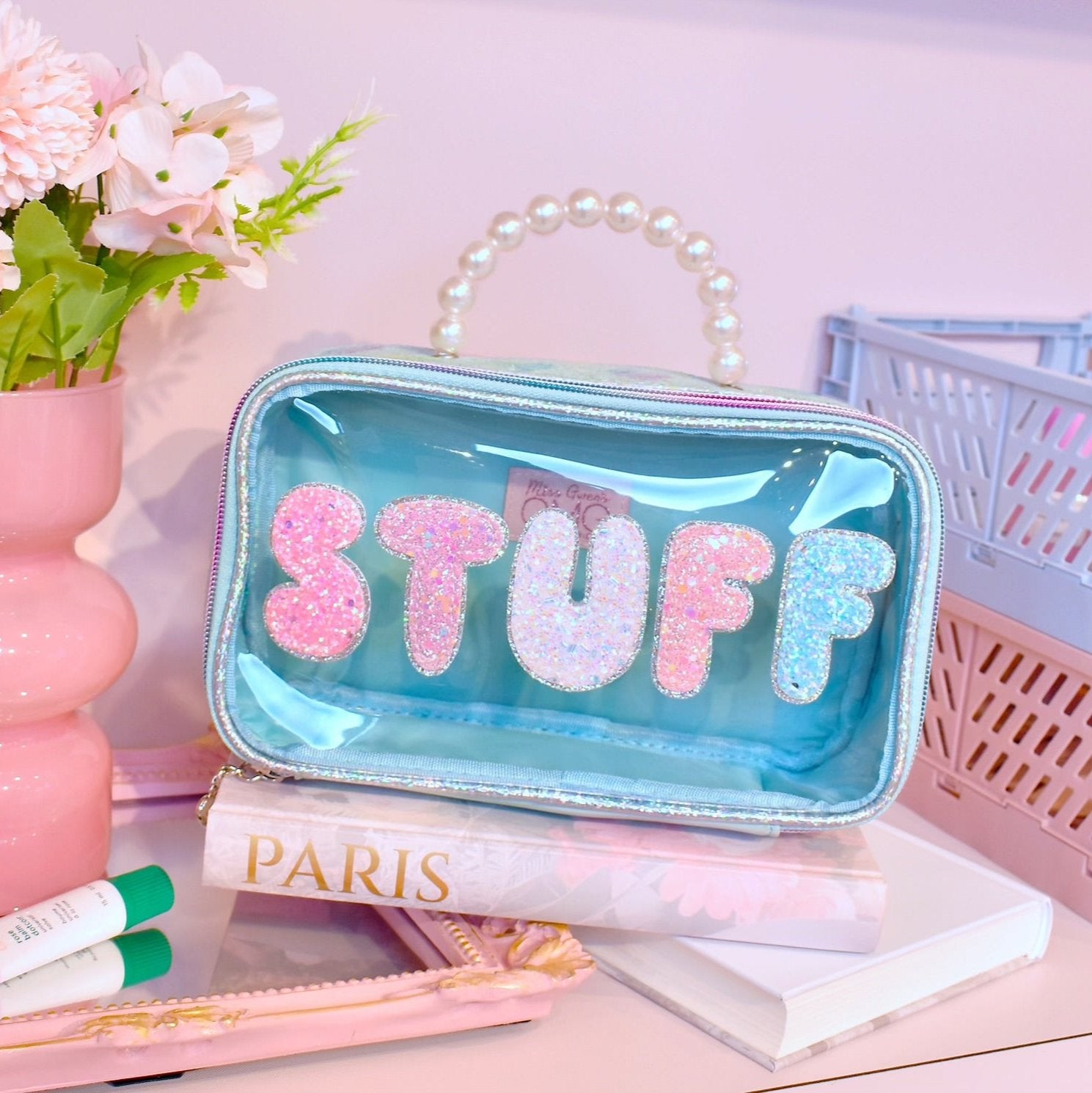 photoshoot photo of a clear pearl top handle pouch with glitter bubble lettering 'stuff'