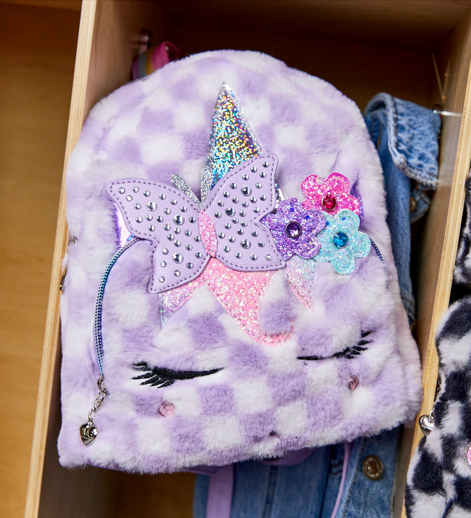 Lifestyle image of lavender checkerboard plush unicorn mini backpack hanging inside cubby